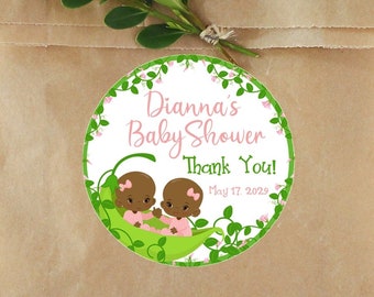 May include: Round sticker with a white background, green vines, pink flowers, and two brown baby dolls in a green pea pod. The text on the sticker reads "Dianna's Baby Shower Thank You! May 17, 2029".