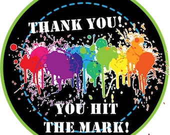 May include: A black circle with a white border and a blue dashed circle inside. The text "THANK YOU!" is at the top of the circle. A rainbow of paint splatters is in the middle of the circle. The text "YOU HIT THE MARK!" is at the bottom of the circle. The word "sample" is in red at the bottom right of the circle.