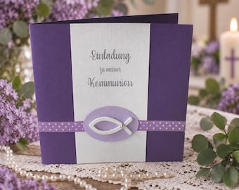 Puede incluir: Una tarjeta cuadrada de color morado y blanco con el texto Einladung zu meiner Kommunion. La tarjeta presenta un panel central blanco, una cinta horizontal morada con lunares y un emblema ovalado morado claro con un pez blanco en el centro.