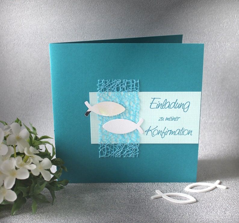 May include: Teal card with a white and light blue fish design and the text "Einladung zu meiner Konfirmation" on a light blue background.