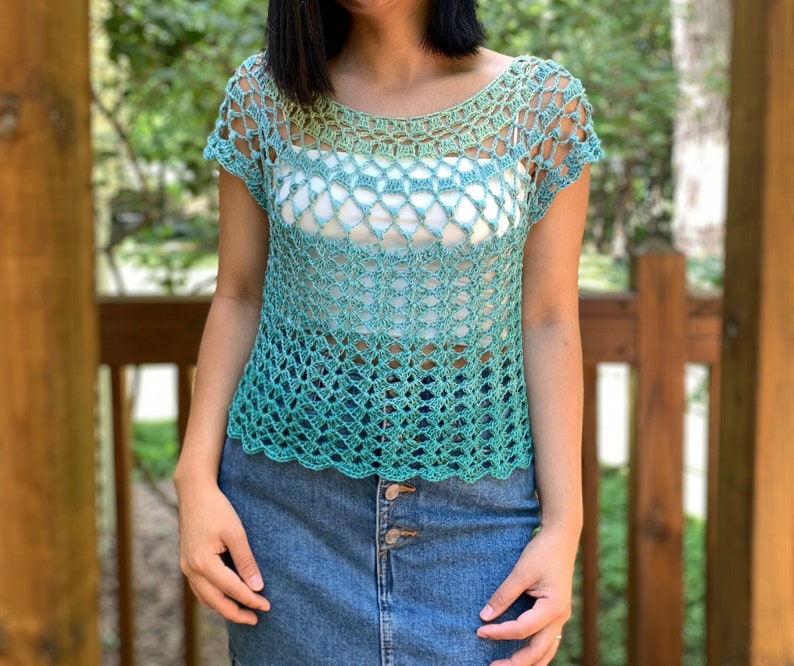 Op de afbeelding: Een gecrochet top met een groen en blauw ombre patroon. De top heeft een ronde hals en korte mouwen. De top is gemaakt met een delicaat open steekpatroon.
