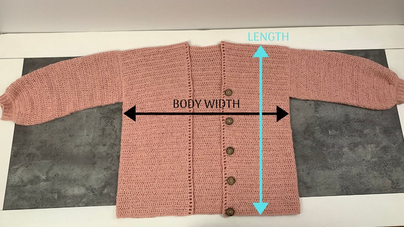 May include: A pink crocheted cardigan with a button closure. The cardigan has long sleeves and a V-neck. The measurements are: Length 23 inches, Body Width 20 inches.