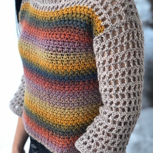 Op de afbeelding: Een gestreept gehaakt topje met een kleurrijk ombre-ontwerp. De mouwen zijn gemaakt met een kant-achtige haaksteek.