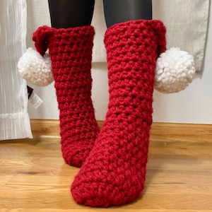 May include: Red crocheted slipper socks with white pom poms on the top.