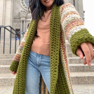 May include: A long, green and multi-colored striped crochet cardigan with a shawl collar.