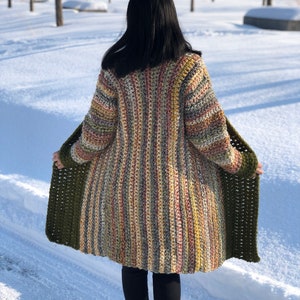 May include: A long, striped cardigan with a green trim. The cardigan is made of a soft, colorful yarn and has a relaxed fit.