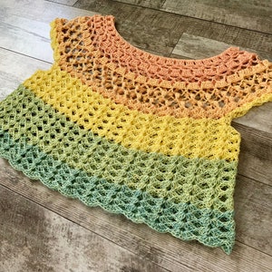 Op de afbeelding: Een veelkleurig gehaakt topje met een regenboogpatroon. Het topje is gemaakt van zacht, lichtgewicht garen en heeft een losse, zwierige pasvorm.