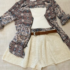 Puede incluir: Una falda de crochet blanca con un cintur&oacute;n marr&oacute;n, un top blanco y una camisa estampada en blanco y negro.