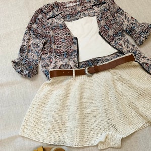 Puede incluir: Falda blanca de crochet con cintur&oacute;n marr&oacute;n y top estampado. La falda es de corte A y tiene un ajuste holgado.