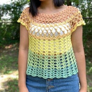 Op de afbeelding: Een gehaakt topje met een regenboog ombre-ontwerp. Het topje heeft een losse pasvorm en korte mouwen. Het is gemaakt van een lichtgewicht garen en heeft een delicaat, opengewerkt patroon.