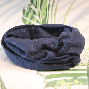 Op de afbeelding: Een donkerblauwe, glinsterende, zachte stof nekwarmer of sjaal. De stof is geplooid en gevouwen om een ​​gezellige, warme look te creëren.