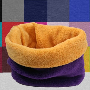 Op de afbeelding: Een omkeerbare fleece nekwarmer met een paarse en gele kleurcombinatie. De nekwarmer is gemaakt van zacht, comfortabel fleece en is perfect om warm te blijven in koud weer.