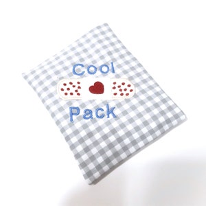 Könnte beinhalten: Ein Kühlpack aus grau-weißem Gingham-Stoff mit blauer Stickerei, auf dem "Cool Pack" und ein rotes Herz auf einem weißen Verband steht.