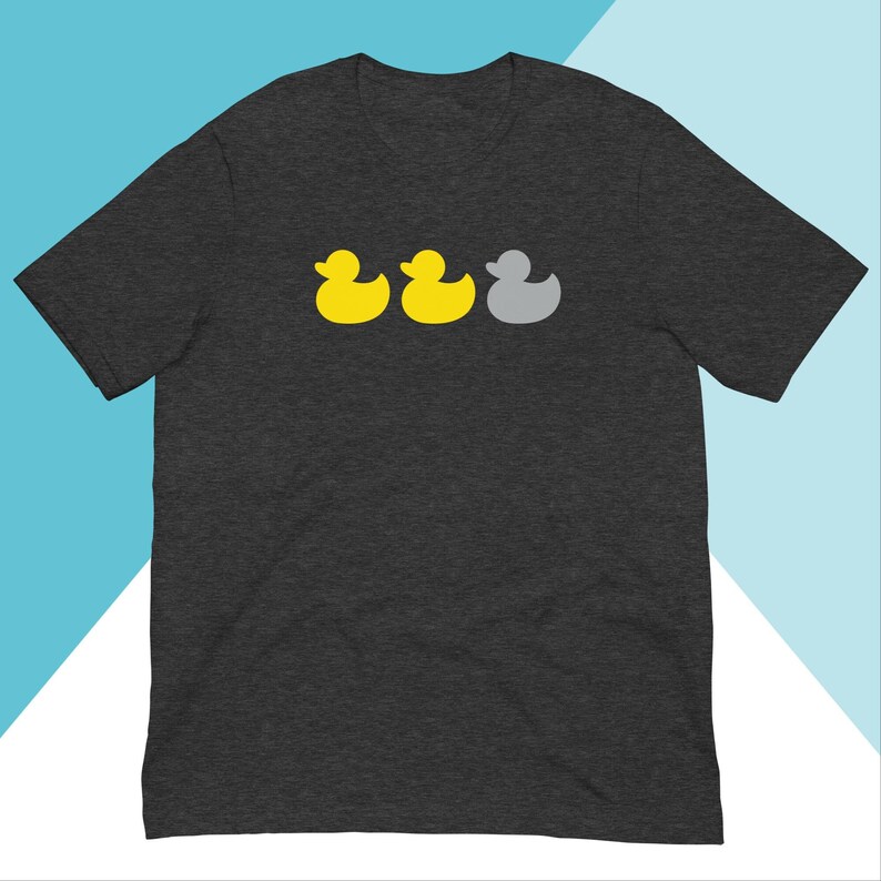 May include: A dark heather grey t-shirt featuring a graphic of three rubber ducks. Two of the ducks are yellow and one is grey.