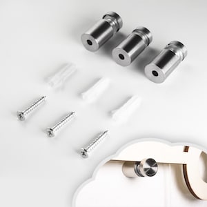 Puede incluir: Tres ganchos de metal plateado con tornillos y tacos de plástico. Los ganchos están diseñados para colgar objetos en una pared.