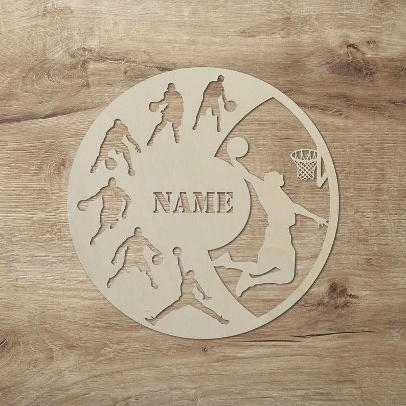 May include: A wooden basketball themed wall decor with silhouettes of basketball players and a basketball hoop. The decor has a space for a name, "NAME", in the center.