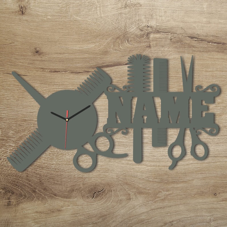 Pu&ograve; includere: Orologio da parete in legno grigio con quadrante rotondo e lancette nere. L'orologio &egrave; decorato con un pettine, delle forbici e una spazzola per capelli. La parola "NAME" &egrave; scritta in grandi lettere sopra l'orologio.