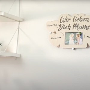 Puede incluir: Marco de fotos de madera con cinco recortes en forma de coraz&oacute;n. El marco tiene el texto "Wir lieben Dich Mama" y una foto de dos chicas. Cada recorte en forma de coraz&oacute;n tiene el texto "Name/Text" escrito en &eacute;l.