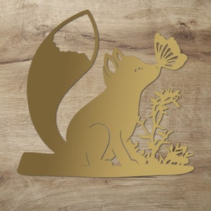 May include: A gold metal cutout of a fox with a butterfly in its mouth. The fox is sitting on a bed of grass.