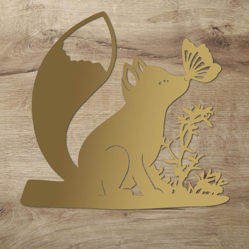 May include: A gold metal cutout of a fox with a butterfly in its mouth. The fox is sitting on a bed of grass.