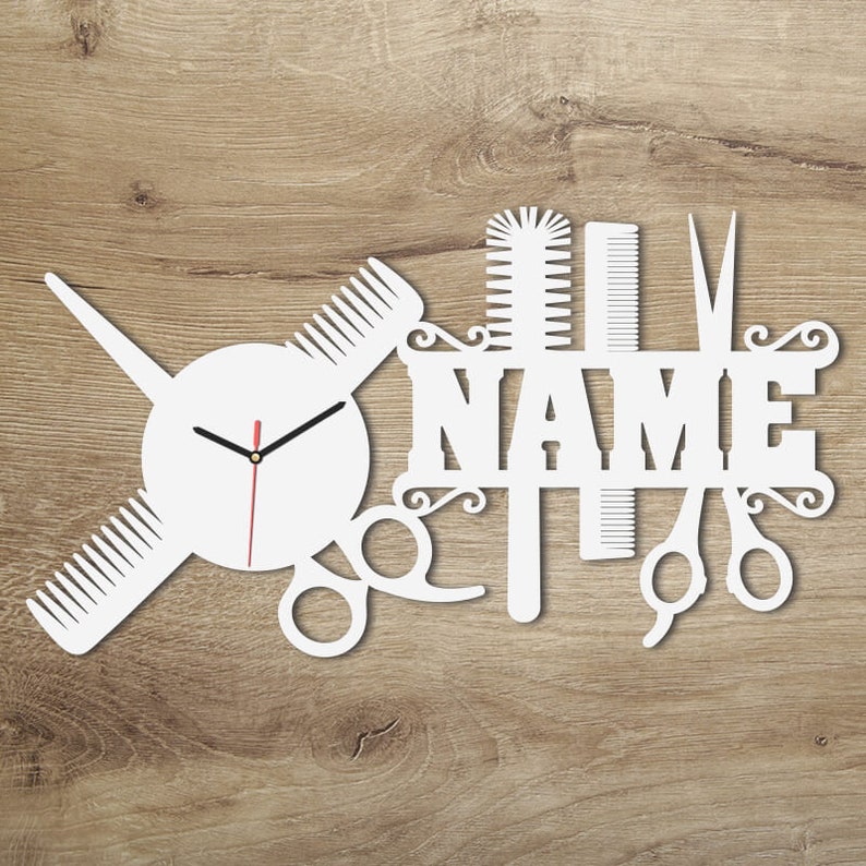 Pu&ograve; includere: Orologio da parete bianco con quadrante rotondo e lancette nere. L'orologio &egrave; circondato da un design di forbici, pettini e una spazzola per capelli. La parola "NAME" &egrave; visualizzata sopra l'orologio.