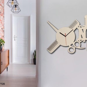 Pu&ograve; includere: Un orologio da parete in legno con sfondo bianco e lancette nere. L'orologio ha la forma di una forbice, un pettine e un rasoio. La parola "NAME" &egrave; scritta in grandi lettere sull'orologio.