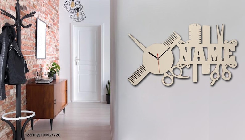 Pu&ograve; includere: Un orologio da parete in legno con sfondo bianco e lancette nere. L'orologio ha la forma di una forbice, un pettine e un rasoio. La parola "NAME" &egrave; scritta in grandi lettere sull'orologio.