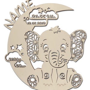 May include: A wooden cutout of an elephant sitting on a crescent moon with stars and clouds. The moon has the text "NAME" and "21:35 Uhr 12.08.2019" on it. The cloud has the text "3120g 52cm" on it.