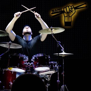 K&ouml;nnte beinhalten: Eine Person spielt ein Schlagzeug mit Drumsticks in der Luft. Die Trommeln sind rot, schwarz und silber. Die Becken sind silber. Der Hintergrund ist schwarz.