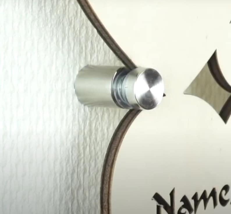 Puede incluir: Un soporte de pared de metal plateado con una tapa redonda de plata pulida. El soporte est&aacute; fijado a una pared blanca.