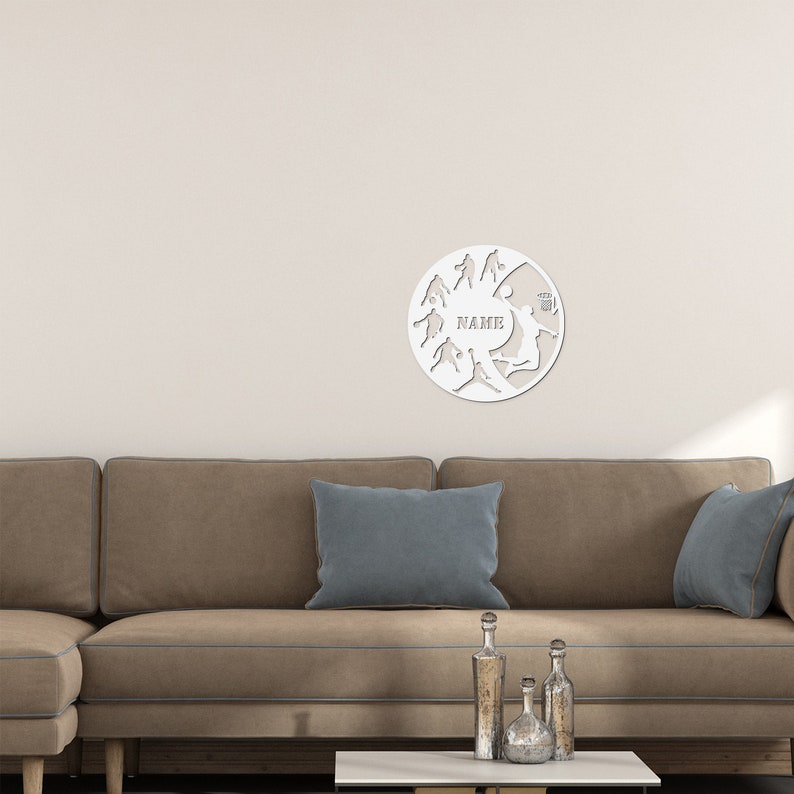 May include: White circular wall decor with a silhouette of various sports players, including basketball, soccer, and volleyball. The word "NAME" is written in the center of the decor.
