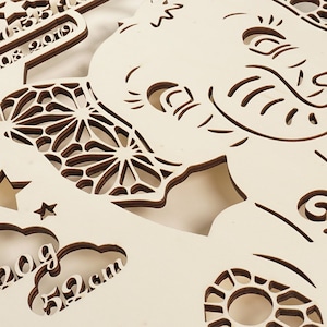 May include: A wooden cutout of an elephant with intricate details, including a floral design and the text "08.2019". The elephant is surrounded by other cutouts, including a star, clouds, and a circle with a floral design. The text "20g" and "52cm" are also visible.