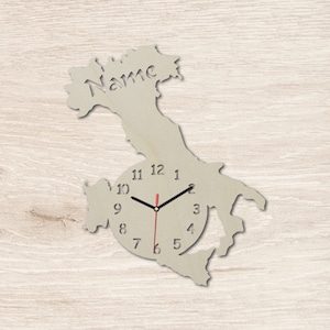 Peut inclure: Une horloge en bois en forme de contour d'un pays avec le mot "Name" gravé en haut. Le cadran de l'horloge est blanc avec des chiffres et des aiguilles noirs.