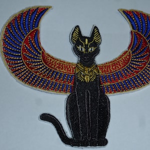 Könnte beinhalten: Gestickter Aufnäher mit einer schwarzen Katze mit goldenen Akzenten, die unter stilisierten Flügeln in Rot, Blau und Gold sitzt. Das Design erinnert an altägyptische Bilder, geeignet für Kleidung oder Accessoires.