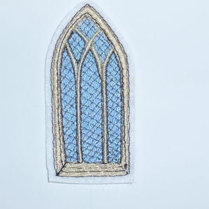 Könnte beinhalten: Gestickter Aufnäher mit einem gotischen Bogenfenster-Design. Das Fenster hat einen hellblauen Hintergrund mit einem Kreuzschraffurmuster, das von goldfarbenen Nähten umrahmt ist. Der Aufnäher befindet sich auf weißem Hintergrund.