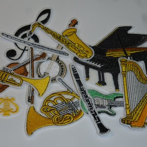 Könnte beinhalten: Gestickte Aufnäher mit verschiedenen Musikinstrumenten, darunter ein Klavier, ein Saxophon, eine Trompete, eine Geige, ein Banjo, eine Harfe und eine Gitarre. Die Aufnäher sind in Gold, Braun, Schwarz und Grün gehalten und haben weiße Ränder. Ein Notenschlüssel ist ebenfalls enthalten.