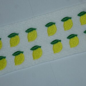 Könnte beinhalten: Gestickte Zitronenaufnäher mit grünen Blättern und leuchtend gelben Früchten. Die Aufnäher sind auf einer weißen Oberfläche angeordnet. Die Zitronenaufnäher haben ein fröhliches und sommerliches Design.