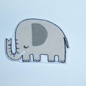 Könnte beinhalten: Gestickter Aufnäher mit einem hellgrauen Elefanten mit einem dunkelgrauen Ohr und schwarzer Umrandung. Der Elefant hat ein kleines Auge und einen detaillierten Rüssel. Geeignet zum Dekorieren von Kleidung, Taschen oder anderen Stoffartikeln.