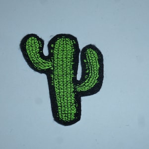Könnte beinhalten: Ein grüner Kaktusaufnäher mit schwarzem Rand. Das Kaktusdesign ist mit einem strukturierten Aussehen gestickt. Der Aufnäher ist ein dekorativer Artikel, der für Kleidung oder Accessoires geeignet ist.
