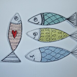 Könnte beinhalten: Vier gestickte Fischaufnäher in verschiedenen Farben. Ein Fisch ist rosa mit einem roten Herzen, ein anderer ist türkis mit einem Rautenmuster, ein dritter ist gelb mit einem Wirbelmuster und der letzte ist blau mit einem Schuppenmuster. Alle haben schwarze Umrisse.
