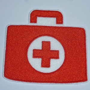 Könnte beinhalten: Gestickter Aufnäher mit einem roten Erste-Hilfe-Kasten-Design und einem weißen Kreuzsymbol in der Mitte. Der Aufnäher hat einen weißen Rand und einen Griff oben, zum Aufnähen oder Aufbügeln auf Stoff.