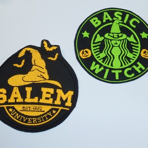 Könnte beinhalten: Zwei gestickte Aufnäher mit Halloween-Motiven. Einer ist schwarz mit einem gelben Hexenhut und den Worten "SALEM UNIVERSITY EST. 1692". Der andere ist ein schwarzer Kreis mit einem grünen Hexen-Design und den Worten "BASIC WITCH".