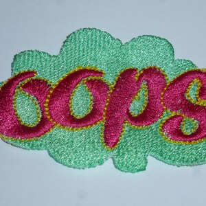 Könnte beinhalten: Gestickter Aufnäher in Form einer Wolke, mit dem Wort "oops" in leuchtendem Pink, gelb umrandet, auf hellgrünem Hintergrund. Der Aufnäher hat ein strukturiertes, genähtes Aussehen.