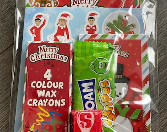 May include: A clear plastic bag containing Christmas-themed items. Includes a red and white crayon box with "Merry Christmas" and "4 Colour Wax Crayons" text, a green candy wrapper, and a red candy. Festive illustrations are visible.