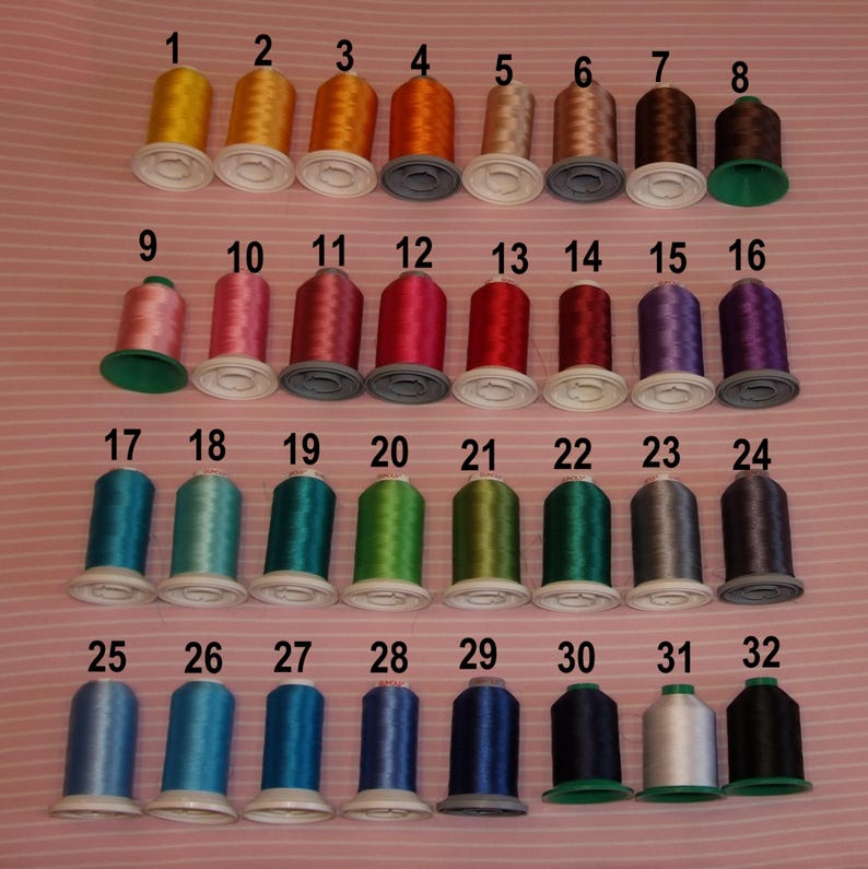 May include: Thirty-two spools of embroidery thread arranged in four rows of eight, each numbered from 1 to 32. The spools feature a wide spectrum of colors including yellow, orange, pink, red, purple, blue, green, brown, gray, white, and black.