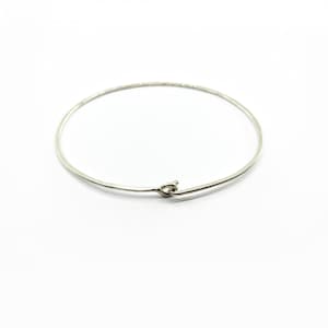 Op de afbeelding: Een eenvoudige zilveren armband met een klein sluiting.