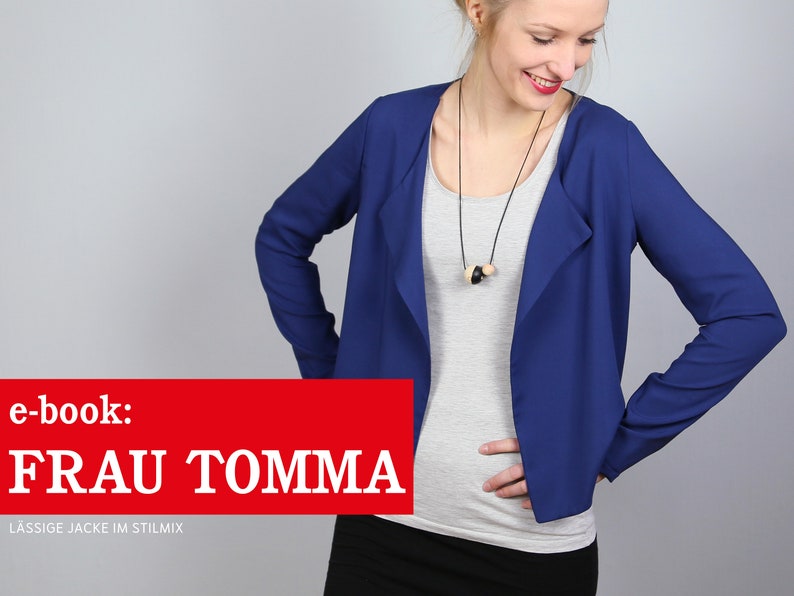 Pode incluir: Uma mulher vestindo um blazer azul com gola drapeada e uma camiseta branca por baixo. O blazer tem mangas compridas e um caimento relaxado. A mulher est&aacute; usando uma saia preta e um colar com contas de madeira. O texto "e-book: FRAU TOMMA L&Auml;SSIGE JACKE IM STILMIX" &eacute; exibido na parte inferior da imagem.