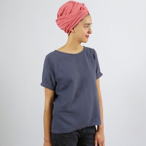 May include: A woman wearing a gray, short-sleeved t-shirt with a pink turban on her head.