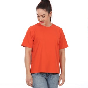 Peut inclure: Un t-shirt à manches courtes de couleur orange vif avec un col rond.