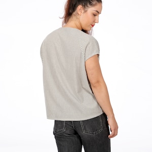 May include: A white and black striped short-sleeved shirt with a relaxed fit. The shirt has a round neckline and a slightly longer back hem.